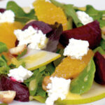 Close up photo of a salad with ricotta, beets, oranges and hazelnuts