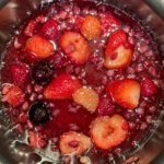 A photo of red berries cooking in syrup.