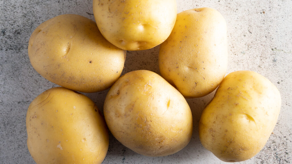 A photo of 6 raw yellow potatoes