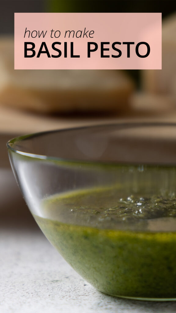 A glass bowl contains freshly made basil pesto.