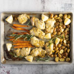 A sheet pan with mustard chicken, potatoes, and carrots