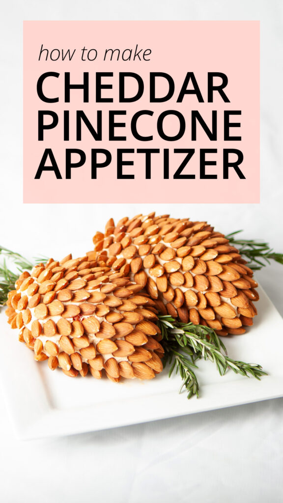 A photo of two pinecone-shaped cheddar spreads, covered with almonds, garnished with rosemary sprigs.