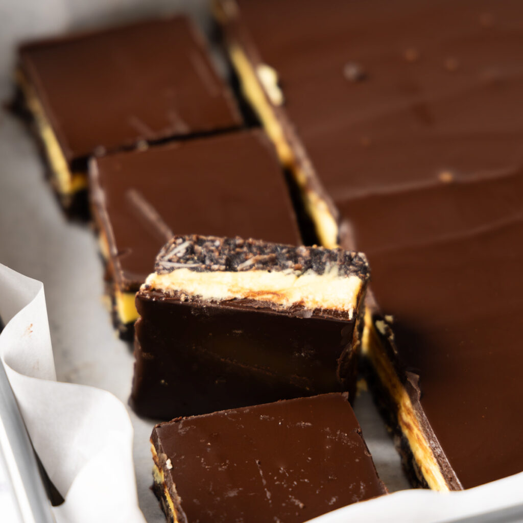 Nanaimo Bars in a tray, sliced into squares.