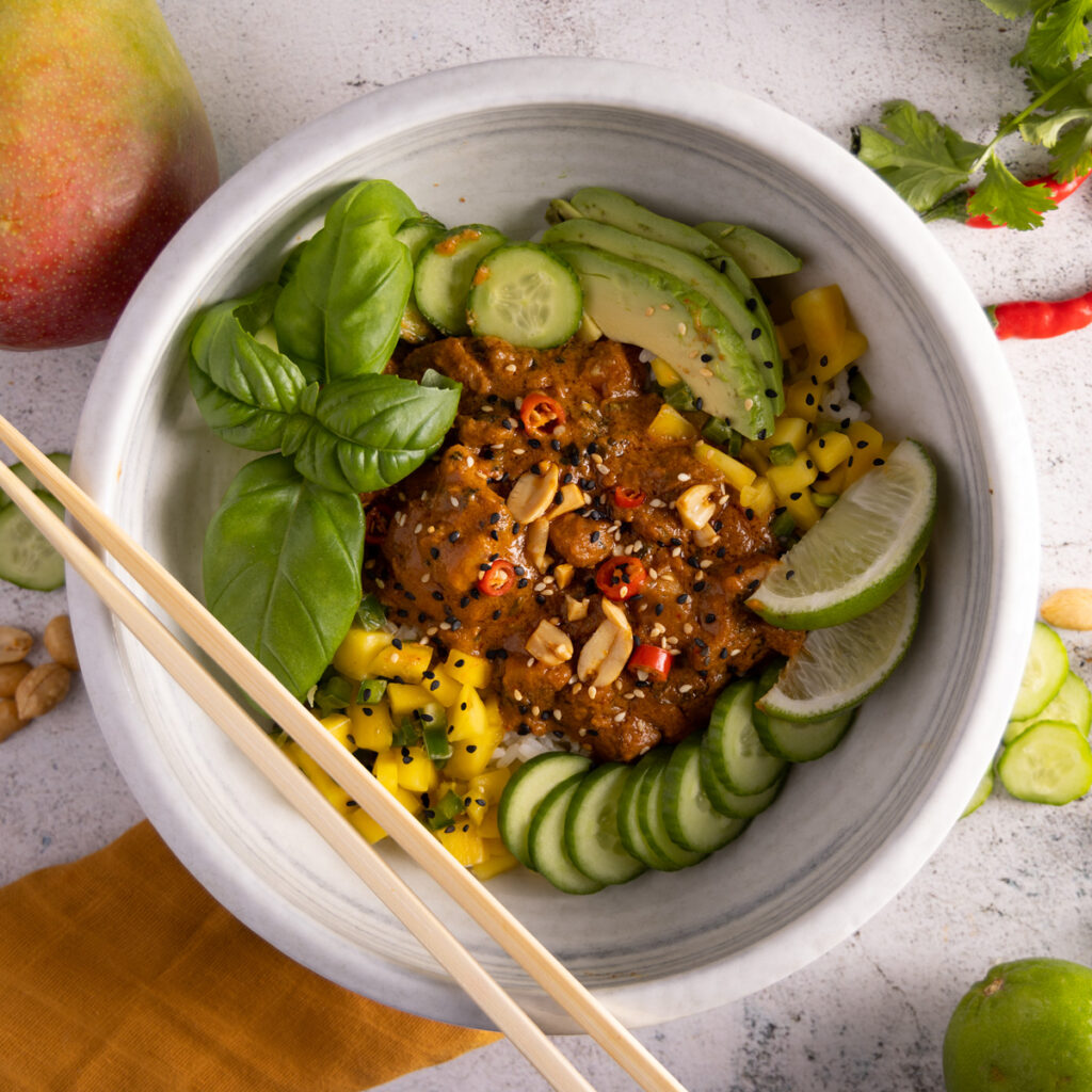 Saucy chicken on top of rice, topped with fresh basil, avocado, mango salsa and sliced cucumbers.