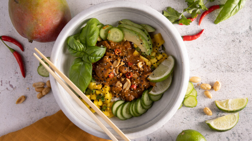 Saucy chicken on top of rice, topped with fresh basil, avocado, mango salsa and sliced cucumbers.