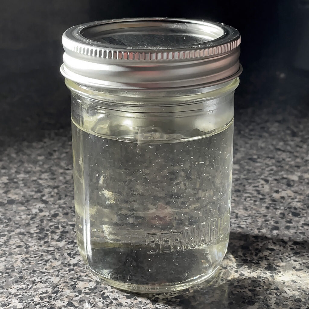 A mason jar containing clear simple syrup. How to make Simple Syrup for cocktails.