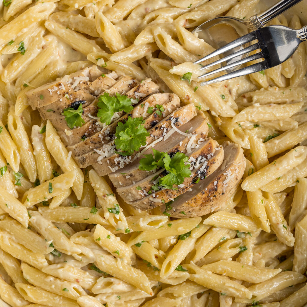 A close-up view of garlic parmesan pasta with grilled chicken.