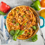 In a large skillet, penne pasta, Italian sausage, sliced bell peppers garnished with fresh basil.