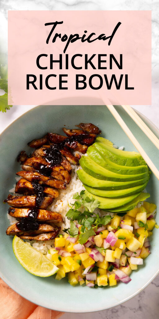 A bowl contains rice, glazed chicken, mango pineapple salsa, sliced avocado. Chopsticks sit on the edge of the bowl, surrounded by a pink napkin, limes, an avocado and a bunch of fresh cilantro.