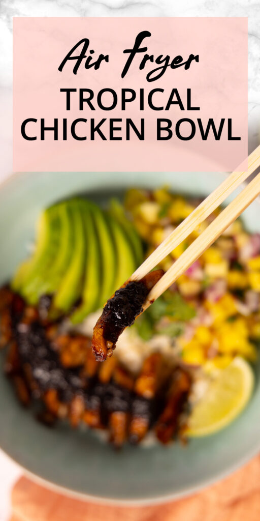 A bowl contains rice, glazed chicken, mango pineapple salsa, sliced avocado. Chopsticks hold a bite of saucy chicken, surrounded by a pink napkin, limes, an avocado and a bunch of fresh cilantro.