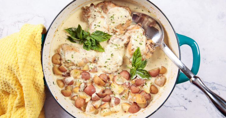 A large skillet with chicken and baby potatoes, in a creamy Dijon mustard sauce.