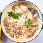 A large skillet with chicken and baby potatoes, in a creamy Dijon mustard sauce.