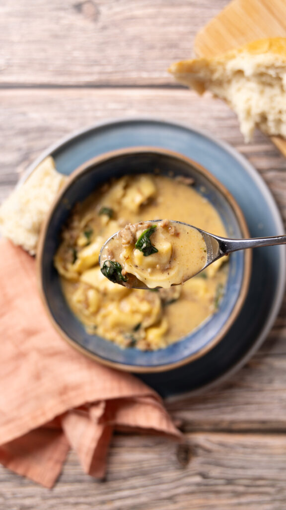 A bowl of creamy sausage, spinach, and tortellini soup.