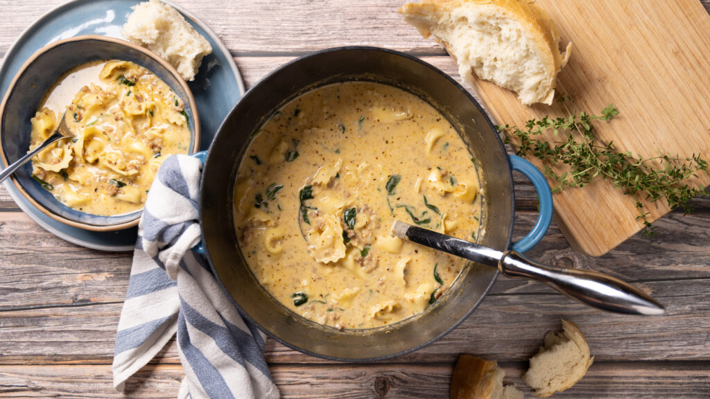 A bowl of creamy sausage, spinach, and tortellini soup.