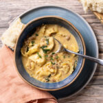 A bowl of creamy sausage, spinach, and tortellini soup.