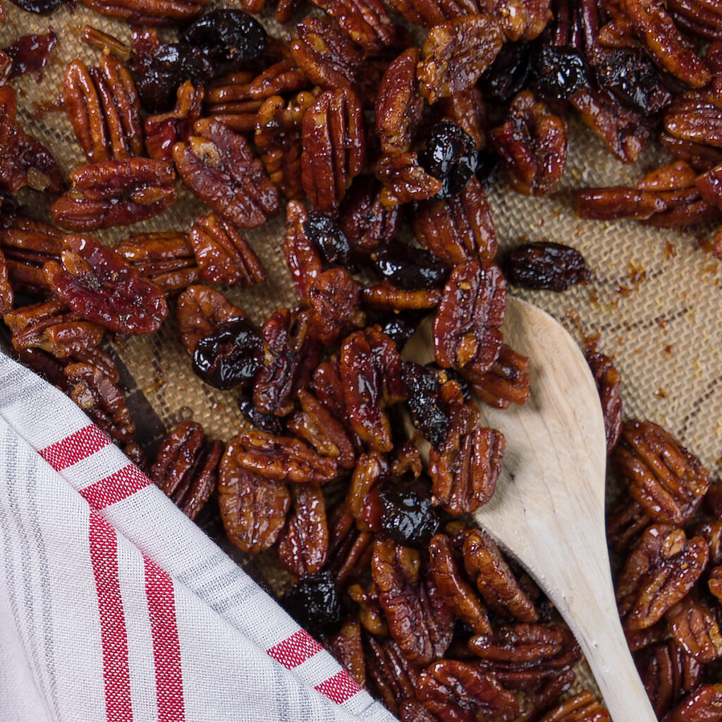 A tray of sweet and spicy glazed pecans with bits of dried cherry and orange zest.