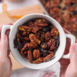 A bowl of sweet and spicy glazed pecans with bits of dried cherry and orange zest.