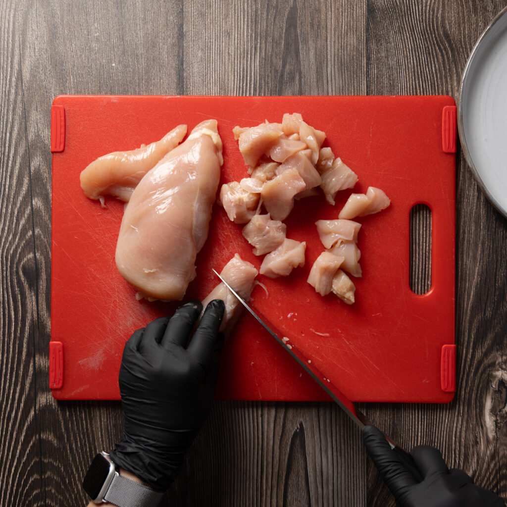 Cutting chicken breast meat into bite-size pieces.