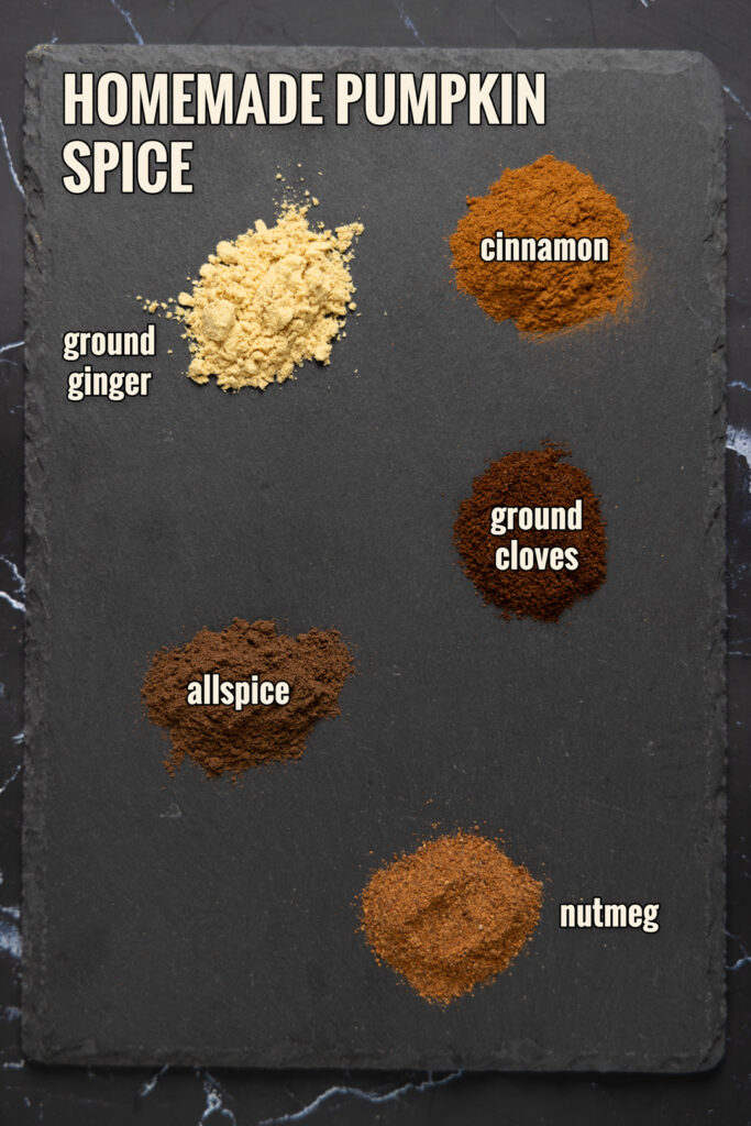Ingredients to make Homemade Pumpkin Spice are arranged on a slate.