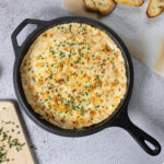A cast-iron skillet with hot and cheesy crab dip.