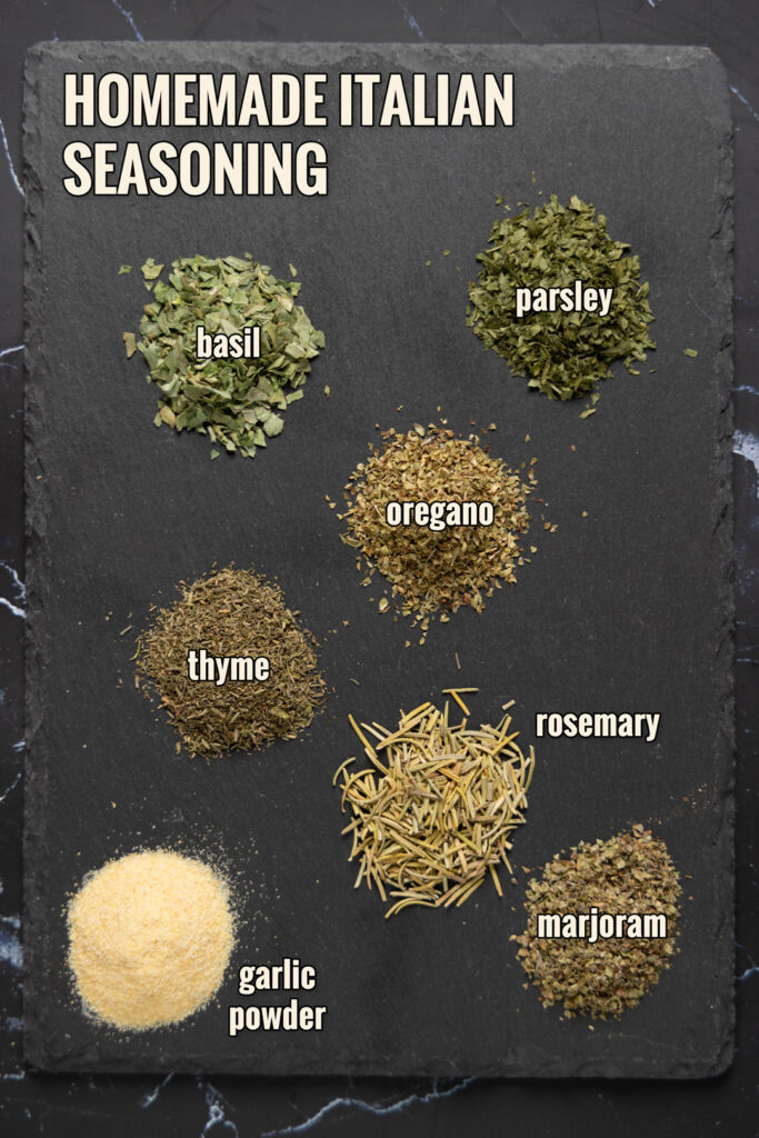 Ingredients to make Homemade Italian Seasoning are arranged on a slate.