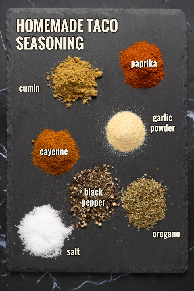 Ingredients to make Homemade Taco Seasoning are arranged on a slate.