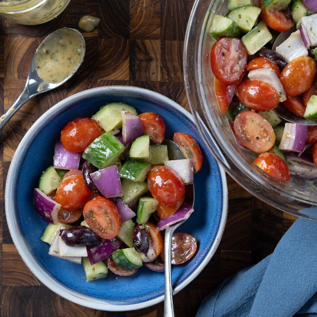 Greek salad containing tomatoes, cucumbers, olives, red onion.