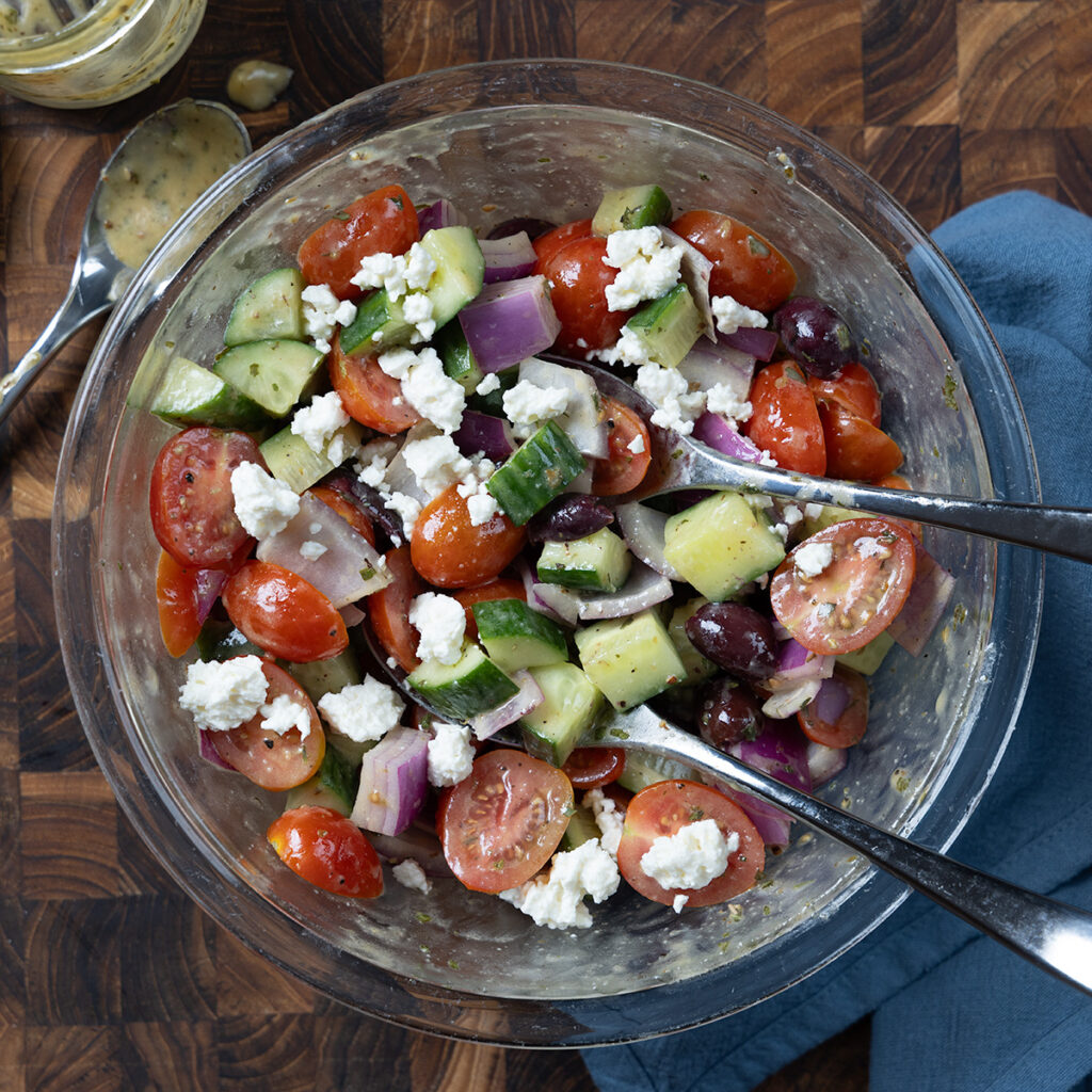 Greek salad containing tomatoes, cucumbers, olives, red onion, and feta cheese.