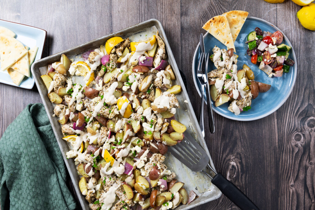 A sheet pan contains greek chicken and potatoes