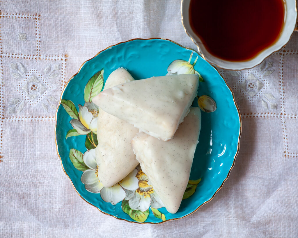 Petite Vanilla Bean Scones on a plate, with a cup of tea.