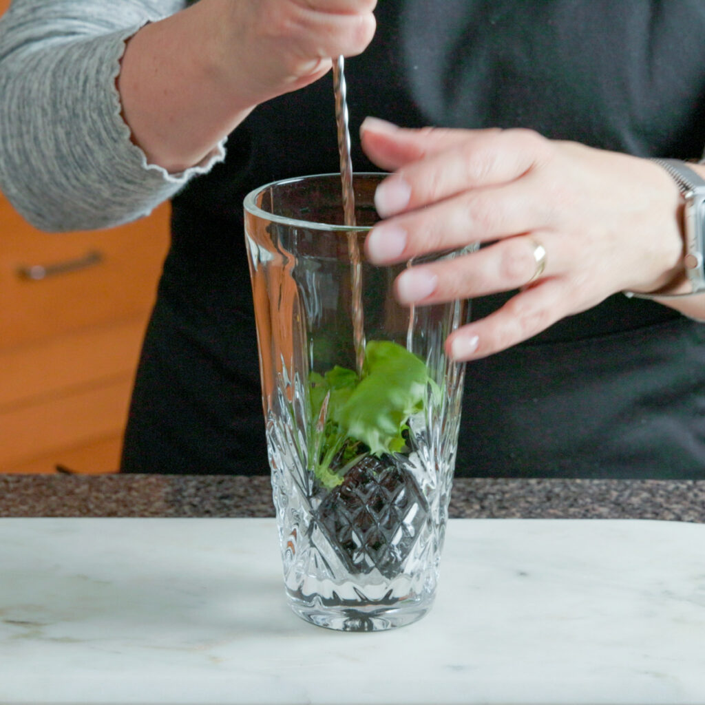 How to make a Blackberry Basil Sour: Muddle blackberries, basil, and sugar in a cocktail shaker.