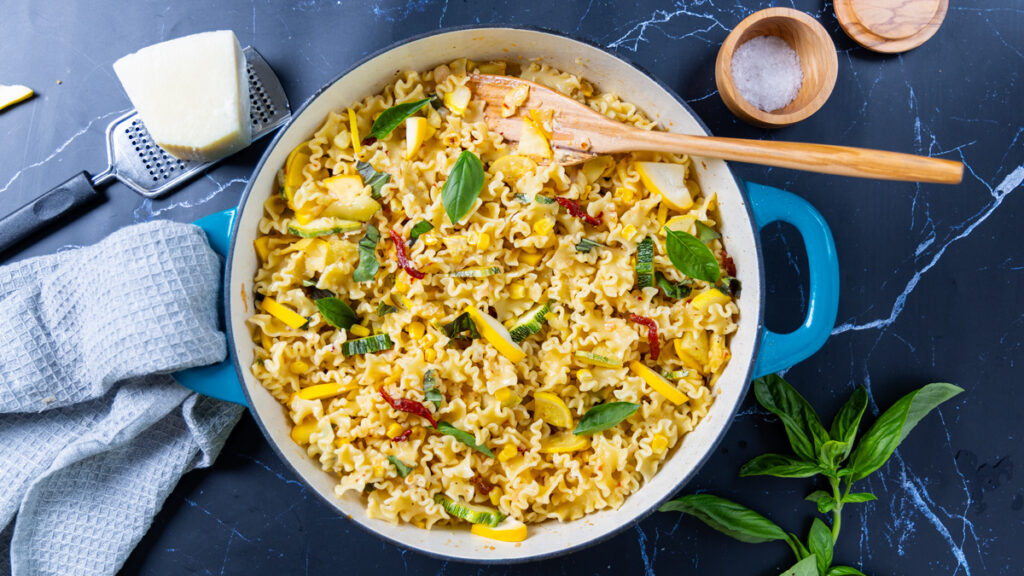 Summer squash pasta in a large skillet, with basil, lemon, red peppers.