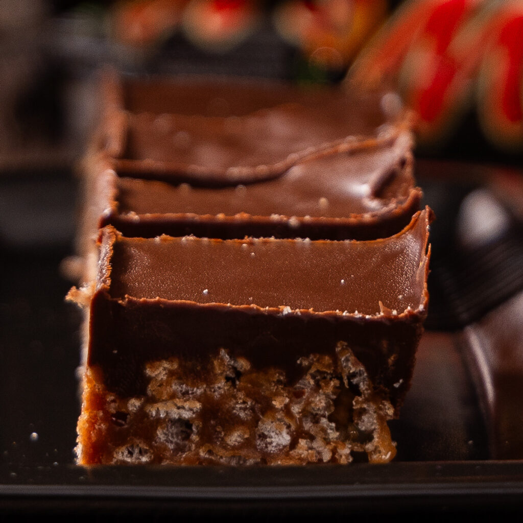 A plate of cut up rice krispie treats, with Mars Bar candy bars in the background.