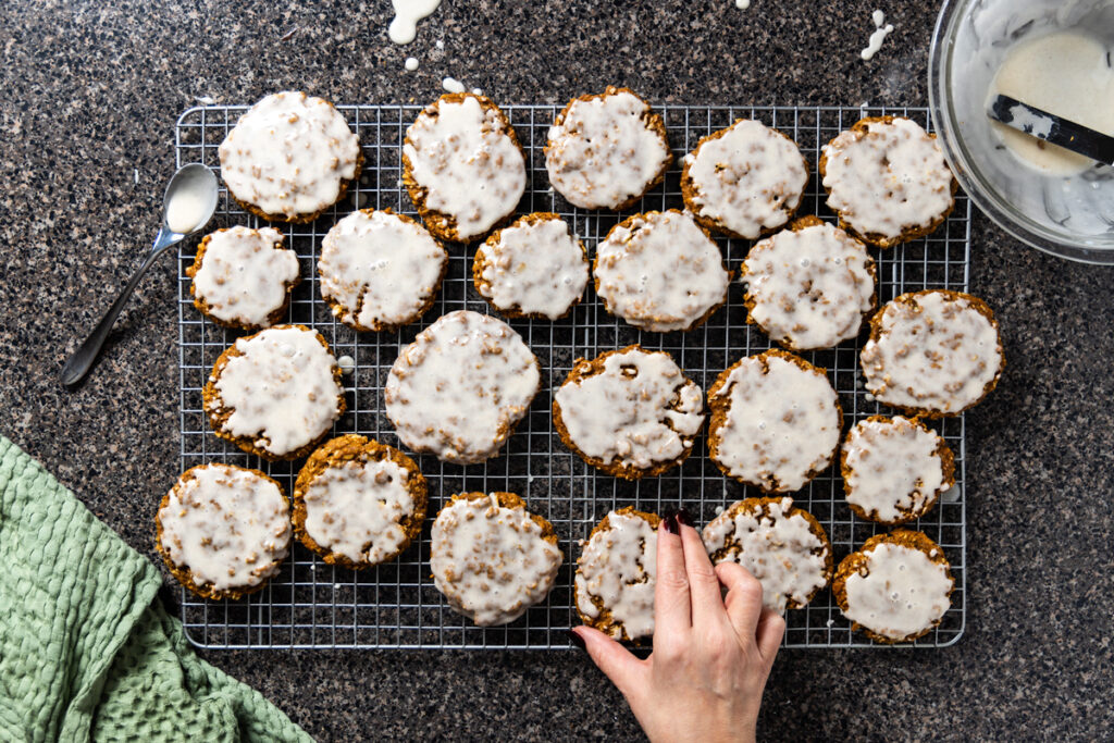 Cookies are arranged on a cooling rack having just been dipped in sweet glaze.