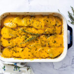 A casserole dish shows a beef and potato layered dish, covered with melted cheese.